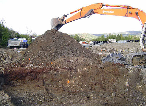 An excavator digging to remove buried drums. 