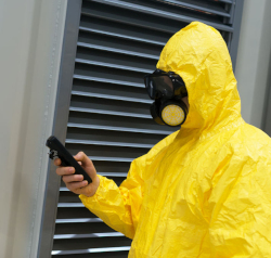 Worker in yellow protective chemical suit checking radiation with geiger counter..