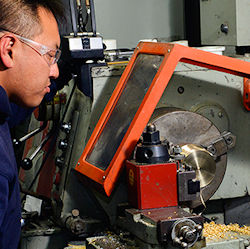 Worker standing in front of table top radial saw and the blade in unguarded