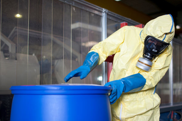 Worker inside in full PPE opening a sealed drum