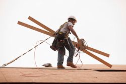 Employee working on roof has fall protection but is carrying too many items