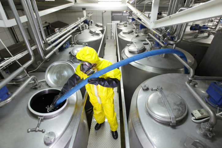 Employee inside cleaning several large tanks all placed in two rows