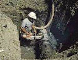 Worker operating a saw in a trench