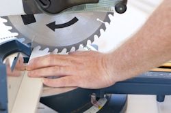 Worker's bare hand very close to saw with no guard 