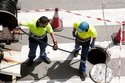 Two workers outside spreading wet cement