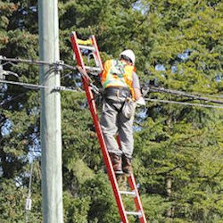 Man on ladder working on voltage wires