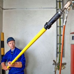 employee holding a long pole with rubber cup designed to reach ceiling bulbs