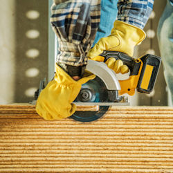 worker wearing gloves while using saw