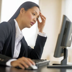 Worker looking stressed and fatigued on computer.