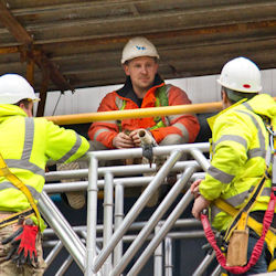 three workers discussing scaffold hazards