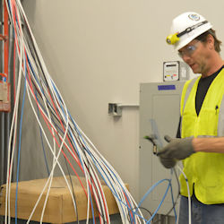 Electrician working on dozens of strands of wiring.