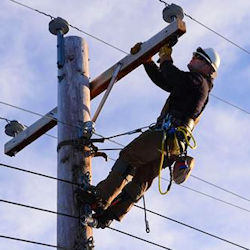 Electricial at top of pole working on high voltage wiring.