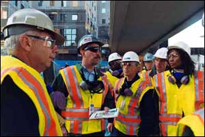 Group of people with safety vests meeting with other companies in the building to coordinate the emergency action plan.