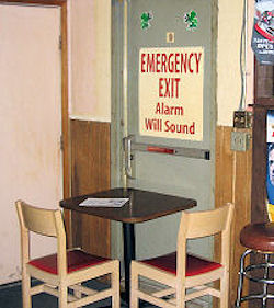 Violation showing a emergency exit door blocked by small table and two chairs.