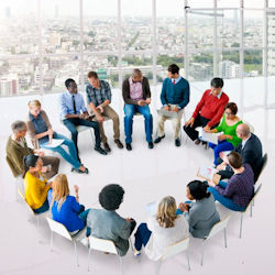 Workers sitting in a circle for a debriefing meeting.