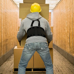 Image of an employee using a back belt while lidting heavy boxes