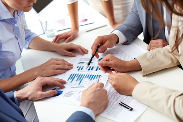 Image of employees around table discussing charts