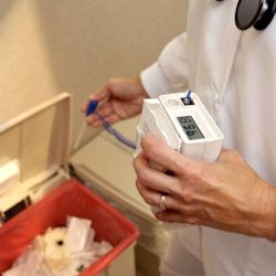 healthcare worker disposing of biohazardous waste in proper container