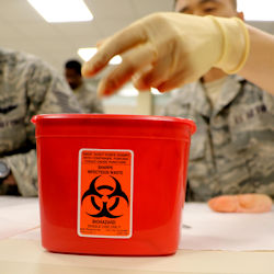 Image of worker depositing items in proper biohazard container.