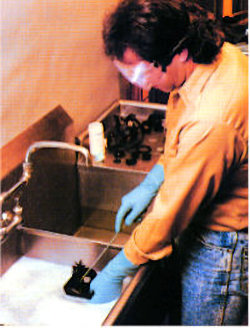 Worker cleaining respirators with gloves and eye protection