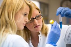 Two lab workers looking at vile of blue liquid