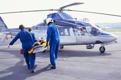 Image of workers loading patient into helicopter with rotating blades hazard.