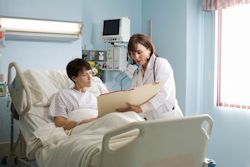 Image of doctor consulting with patient in hospital bed.