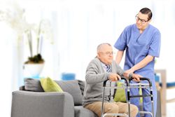 Image of a nurse helping patient to stand using a walker.