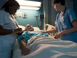 Image of two nurses with patient in hospital bed