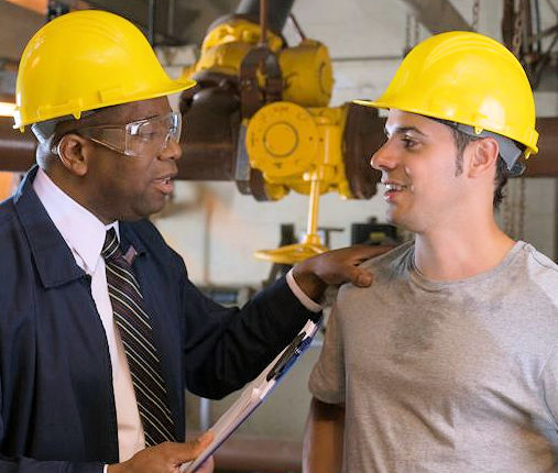 Supervisor and employee talking to each other and wearing hard hats.