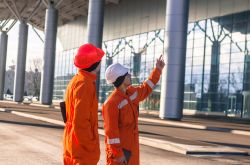 Two workers outside a building looking up