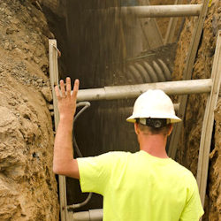 Worker entering a deep trench using a ladder.