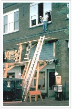 Lean-to scaffold with a worker climbing into a window.