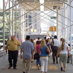 Crowd of people waling under scaffold with covered for protection from falling objects