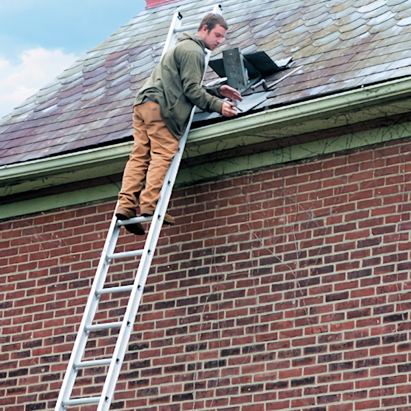 Worker working on roof while standing on ladder