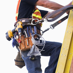 Worker carrying tools in a tool belt while climbing ladder