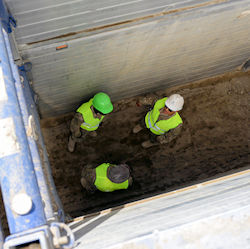 Three workers inspecting a trench