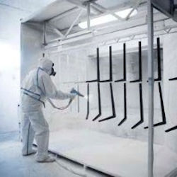 Indoor worker fully suited with PPE while spray painting