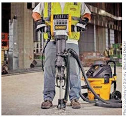 Worker using a jack hammer with a vacuum dust collection system.