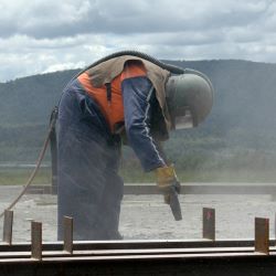 Ourdoor work with PPE  while abrasive blasting beam