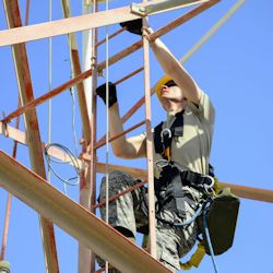 construction worker climbing to the top of a building under construction with a tool belt