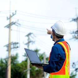 Image of worker holding a laptop computer checking utility lines.