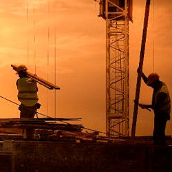 Two Construction workers moving materials around a crane