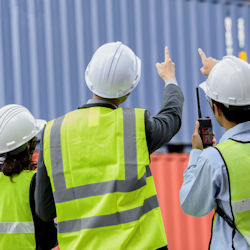 Image of employees outside a building pointing up towards a safety concern 