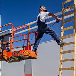 construction worker stepping from a platform to a ladder clearly beyond safety limits