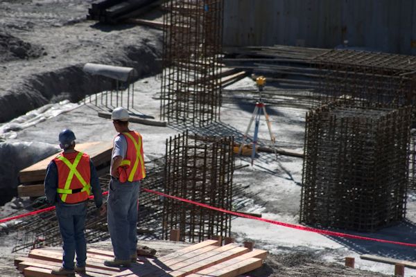 Two workers on a construction site looking for safety hazards