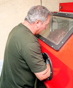 Image of worker using an enclosure to remove paint