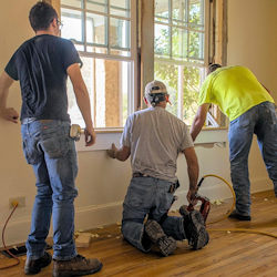 Three workers replacing old windows