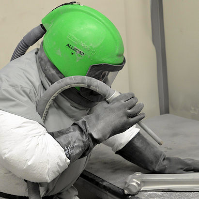 Worker in full PPE sand blasting