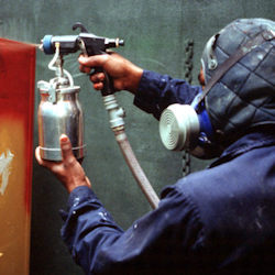 worker with respirator spraying paint